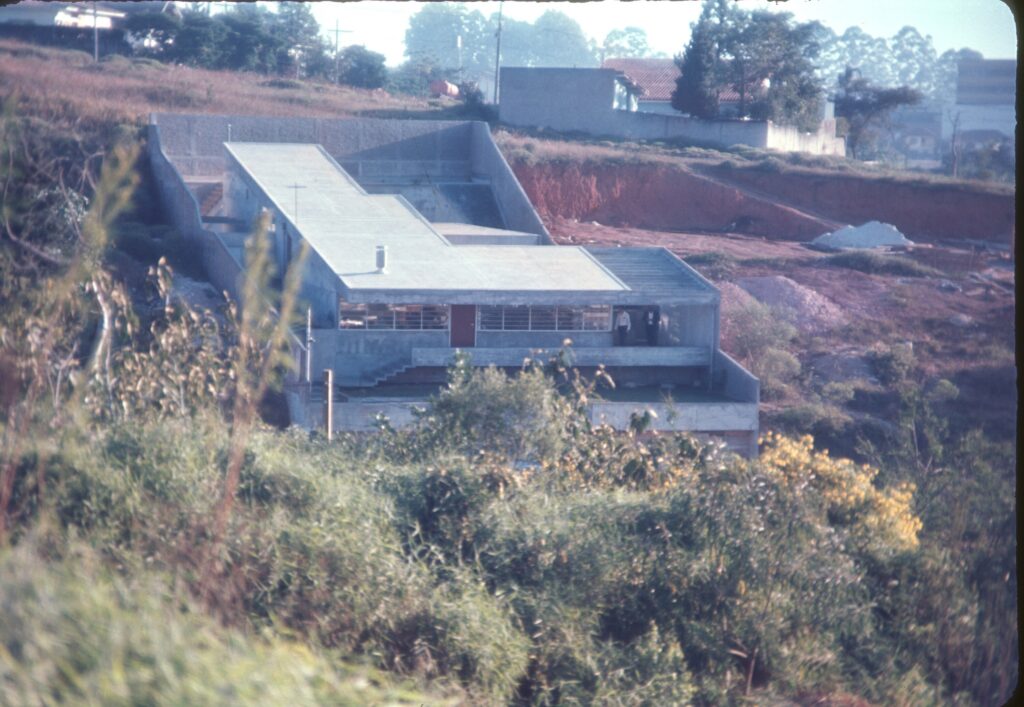 A obra vista de longe, com a laje inclinada e o terraço sobre o talude — P0005 — Residência Celso Monteiro Lamparelli, Jardim Guedala — F016-P0005-1964-S03-D00002