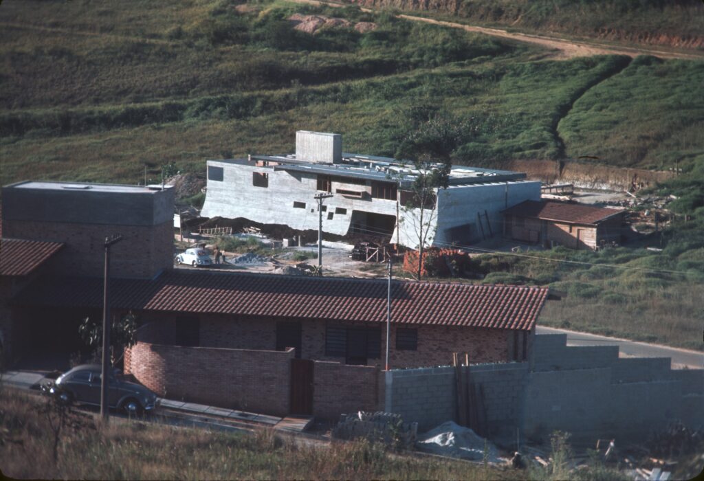 A obra vista de cima, com casas de telha cerâmica em primeiro plano — P0006 — Residência Luiz Carlos Bresser Pereira, Jardim Guedala — F016-P0006-1967-S03-D00007