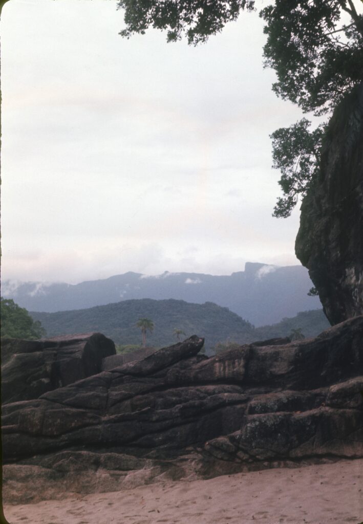 Lajes de rocha à beira da praia, com a serra encoberta ao fundo — P0007 — Residência Luiz França, Praia do Lázaro, Ubatuba — F016-P0007-1965-S03-D00004