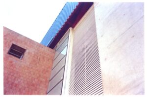 Detalhe do encontro de fachadas: painel ripado, revestimento de pastilhas e cobertura ondulada — P0131 — SESC - Piracicaba