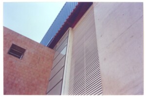 Detalhe do encontro de fachadas: painel ripado, revestimento de pastilhas e cobertura ondulada — P0131 — SESC - Piracicaba