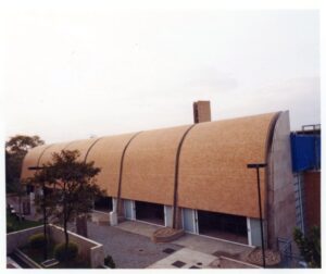Fachada curva de edifício em tijolos aparentes, com janelas estreitas e jardim ao fundo — P0131 — SESC - Piracicaba