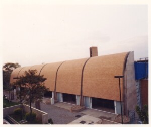 Fachada curva de edifício em tijolos aparentes, com janelas estreitas e jardim ao fundo — P0131 — SESC - Piracicaba
