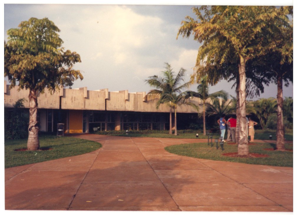 Fachada de edifício térreo com pátio ajardinado e pessoas conversando próximas às árvores — P0015 — SESI — Ribeirão Preto — F009-P0015-1973-S03-D00046