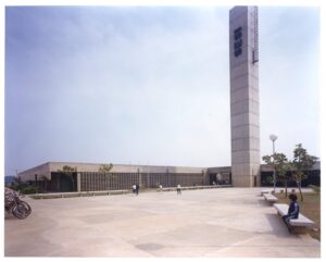 Fachada do edifício SESI, com pátio pavimentado, grades de ventilação e pessoas circulando nas proximidades — P0055 — SESI — São José dos Campos