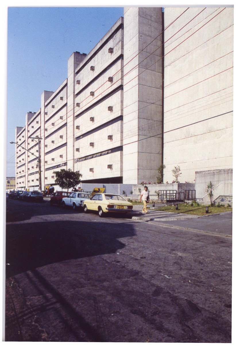 Fachada modulada em concreto aparente, vista em perspectiva ascendente, com veículos estacionados ao fundo e talude de terra ao fundo — P0018 — Correios — Sede Regional e Centro de Triagem — F009-P0018-1975-S03-D00024