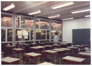 Interior de sala de aula com fileiras de carteiras, lousa e esquadrias de vidro com vista para área verde — P0015 — SESI — Ribeirão Preto