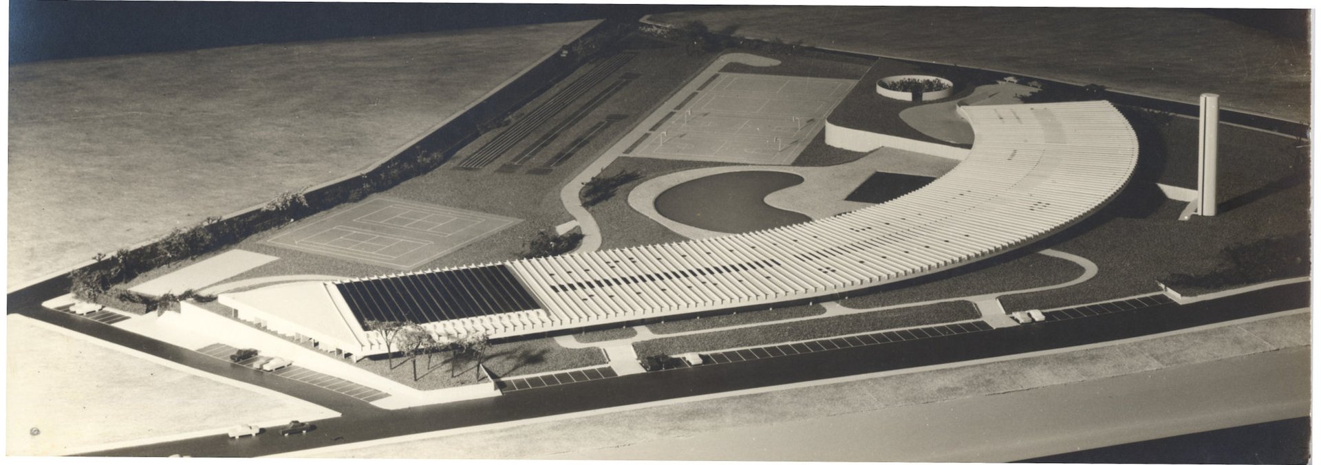 Vista aérea de edifício com cobertura curva em forma de leque, piscina circular e quadras poliesportivas ao lado — P0015 — SESI — Ribeirão Preto — F009-P0015-1973-S03-D00015