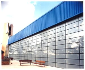 Vista ascendente da fachada de vidro e cobertura metálica azul de edifício do SESC — P0131 — SESC - Piracicaba