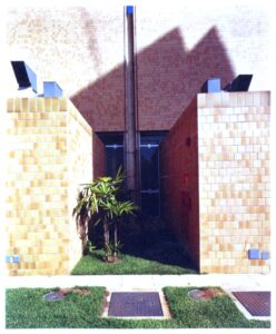 Vista de corredor externo entre volumes revestidos em pastilha cerâmica, com gramado e tampas de inspeção visíveis acima — P0131 — SESC - Piracicaba