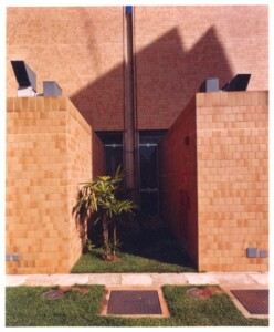 Vista de corredor externo entre volumes revestidos em pastilha cerâmica, com gramado e tampas de inspeção visíveis acima — P0131 — SESC - Piracicaba