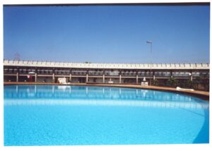 Vista de piscina com edifício de fachada contínua e pilotis ao fundo — P0015 — SESI — Ribeirão Preto