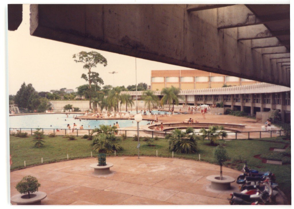 Vista de piscina e área de lazer com estrutura de concreto aparente e pessoas banhistas — P0015 — SESI — Ribeirão Preto — F009-P0015-1973-S03-D00047