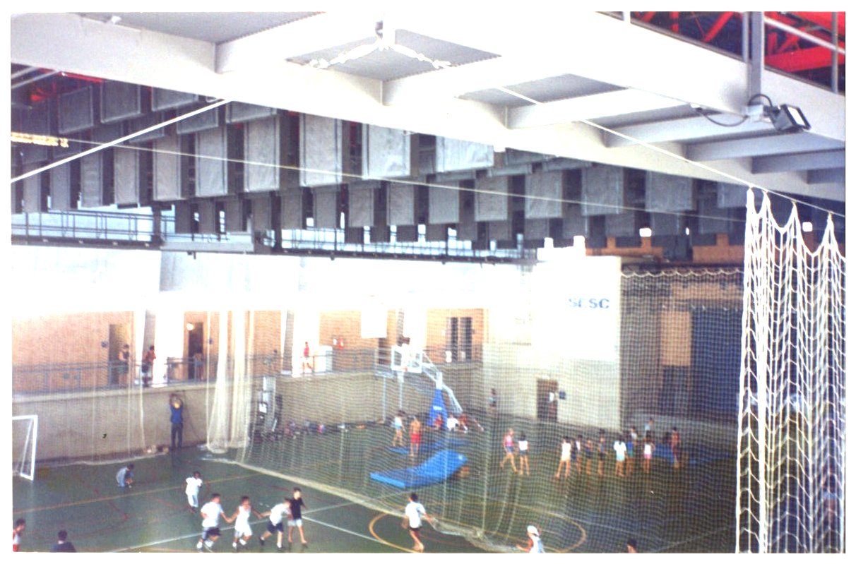 Vista de quadra poliesportiva coberta com estrutura metálica aparente, redes de proteção e pessoas praticando esportes — P0131 — SESC - Piracicaba — F009-P0131-0000-S03-D00043