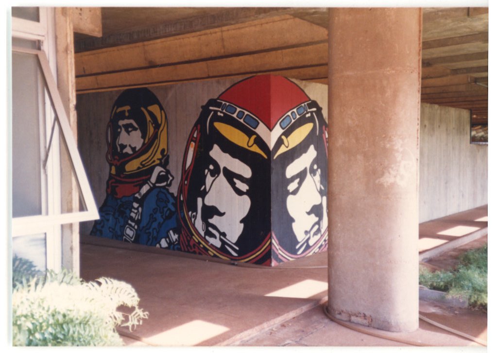Vista de um mural com figuras capacetadas pintado em painel, enquadrado por elementos estruturais de um edifício — P0015 — SESI — Ribeirão Preto — F009-P0015-1973-S03-D00063