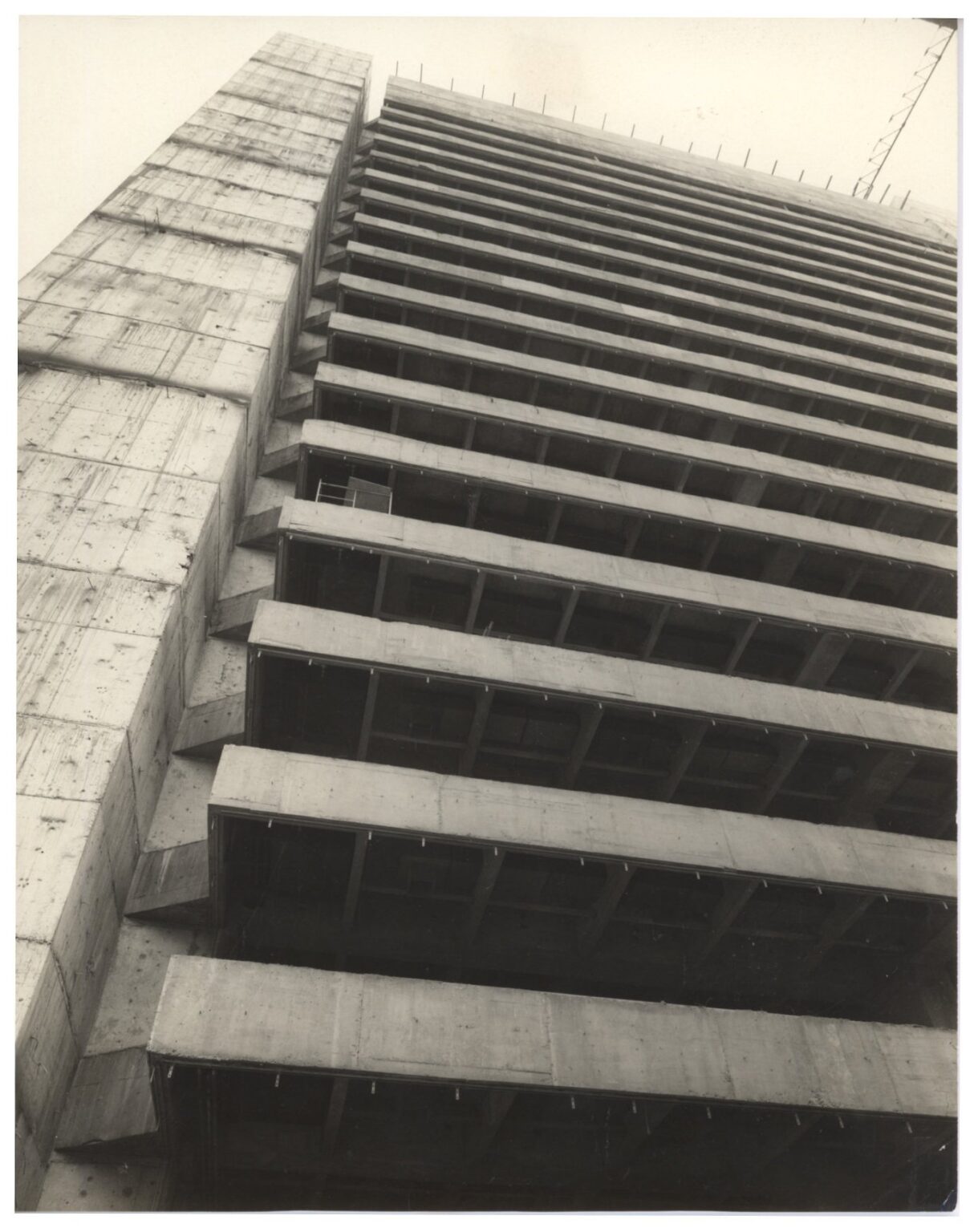 Vista em perspectiva ascendente de edifício em concreto aparente, destacando as lajes em balanço e a estrutura de um volume adjacente — P0018 — Correios — Sede Regional e Centro de Triagem — F009-P0018-1975-S03-D00006