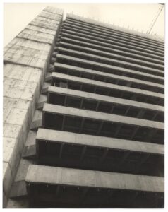 Vista em perspectiva ascendente de edifício em concreto aparente, destacando as lajes em balanço e a estrutura de um volume adjacente — P0018 — Correios — Sede Regional e Centro de Triagem