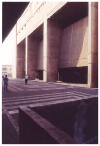 Vista em perspectiva de estrutura modular de concreto com caixas sequenciais, com pessoas caminhando sobre a passarela superior — P0018 — Correios — Sede Regional e Centro de Triagem