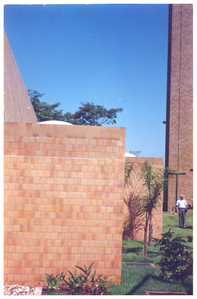 Vista externa de telhado de telhas cerâmicas e parede de tijolos, com árvore e pessoa ao fundo — P0131 — SESC - Piracicaba — F009-P0131-0000-S03-D00053