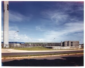 Vista externa do conjunto do SESI, com torre vertical ao fundo, quadra poliesportiva e edifícios em concreto e vidro — P0060 — SESI — Marília