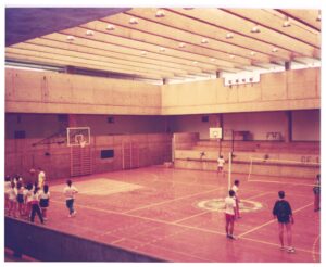 Vista interior de pavilhão gimnodesportivo com pessoas a jogar basquetebol e voleibol — P0015 — SESI — Ribeirão Preto
