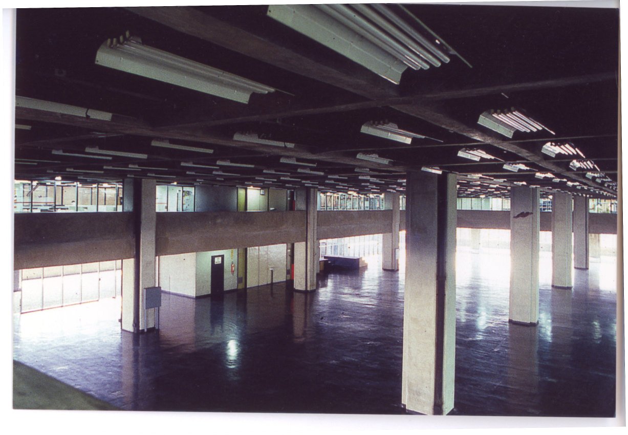 Vista interna de amplo pavimento desocupado, com pilares de concreto, piso escuro reflexivo e luminárias fluorescentes no teto — P0018 — Correios — Sede Regional e Centro de Triagem — F009-P0018-1975-S03-D00026