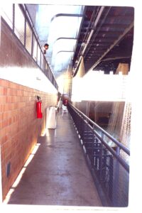 Vista interna de galeria técnica com passarelas metálicas sobrepostas e estrutura de concreto aparente — P0131