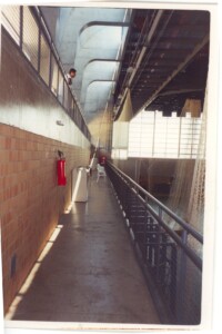 Vista interna de galeria técnica com passarelas metálicas sobrepostas e estrutura de concreto aparente — P0131 — SESC - Piracicaba