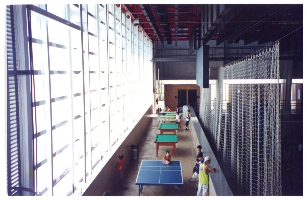 Vista interna de ginásio esportivo com mesas de tênis de mesa, cobertura em painéis translúcidos e rede de proteção suspensa — P0131 — SESC - Piracicaba — F009-P0131-0000-S03-D00046