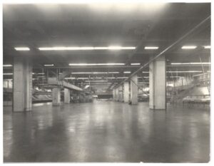 Vista interna de nave industrial mostrando estrutura de vigas de concreto e sistema de iluminação — P0018 — Correios — Sede Regional e Centro de Triagem