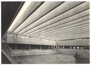 Vista interna de obra em andamento, mostrando cobertura em vigas de concreto armado e piso térreo inacabado — P0015 — SESI — Ribeirão Preto