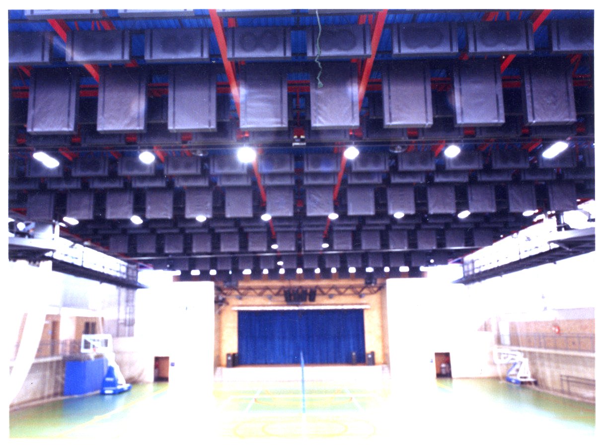 Vista interna de quadra poliesportiva coberta, com estrutura metálica aparente no teto, palco com cortina azul ao fundo e piso de quadra demarcado — P0131 — SESC - Piracicaba — F009-P0131-0000-S03-D00031