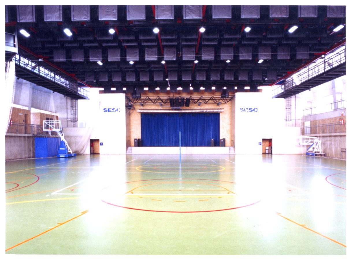 Vista interna de quadra poliesportiva coberta, com piso demarcado para diversas modalidades e palco com cortina azul ao fundo — P0131 — SESC - Piracicaba — F009-P0131-0000-S03-D00030