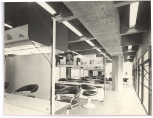 Vista interna de salão com cadeiras reclináveis e estante de produtos, estrutura de concreto aparente ao fundo — P0112 — SENAC — Av. Francisco Matarazzo