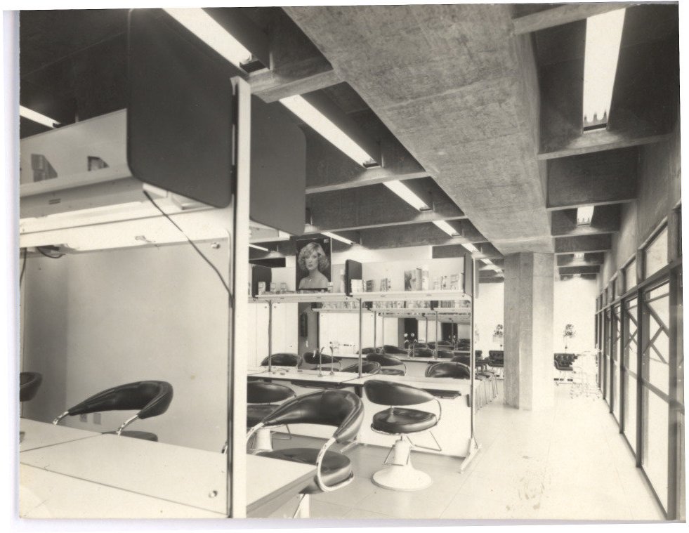 Vista interna de salão com cadeiras reclináveis e estante de produtos, estrutura de concreto aparente ao fundo — P0112 — SENAC — Av. Francisco Matarazzo — F009-P0112-1972-S03-D00002